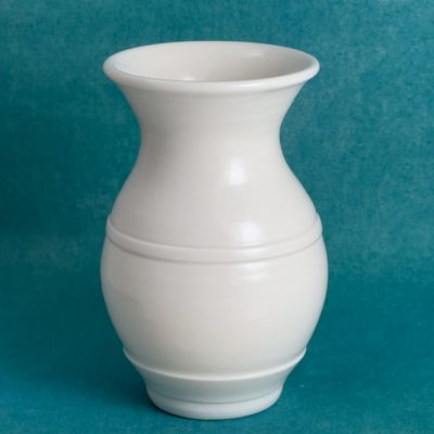 Vase blanc en porcelaine avec un col évasé, un corps arrondi et une fine ligne à mi-hauteur, sur fond turquoise.
